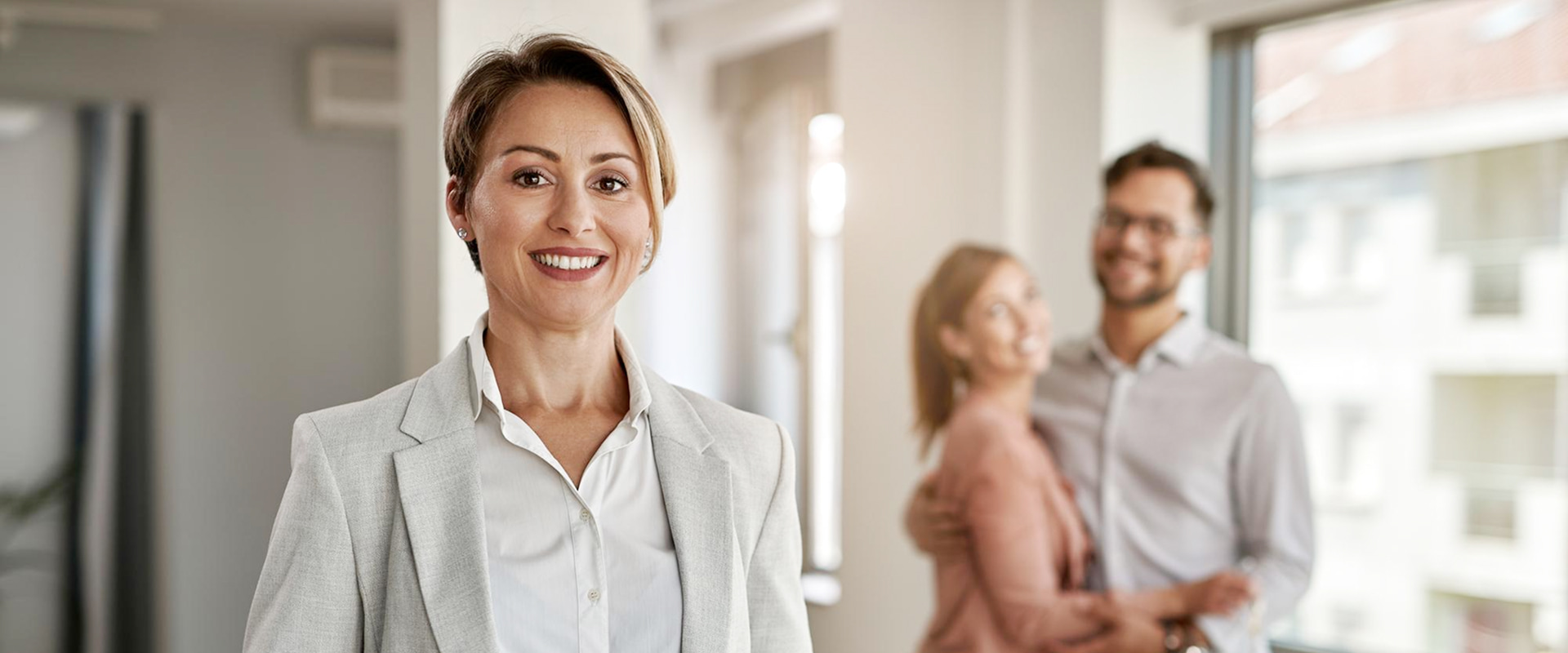 Immobilienmaklerin Mit Käuferpaar Im Hintergrund